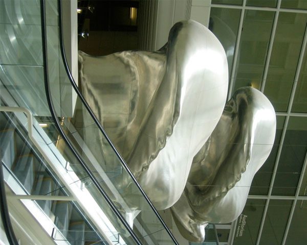 A mirror reflecting the reflection of two silver statues.