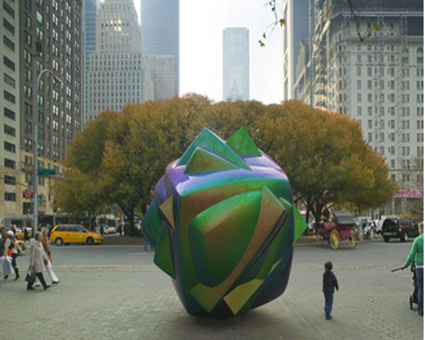 A large sculpture of a green and blue ball in the middle of a city.