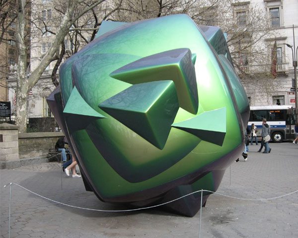 A green and black sculpture on the ground